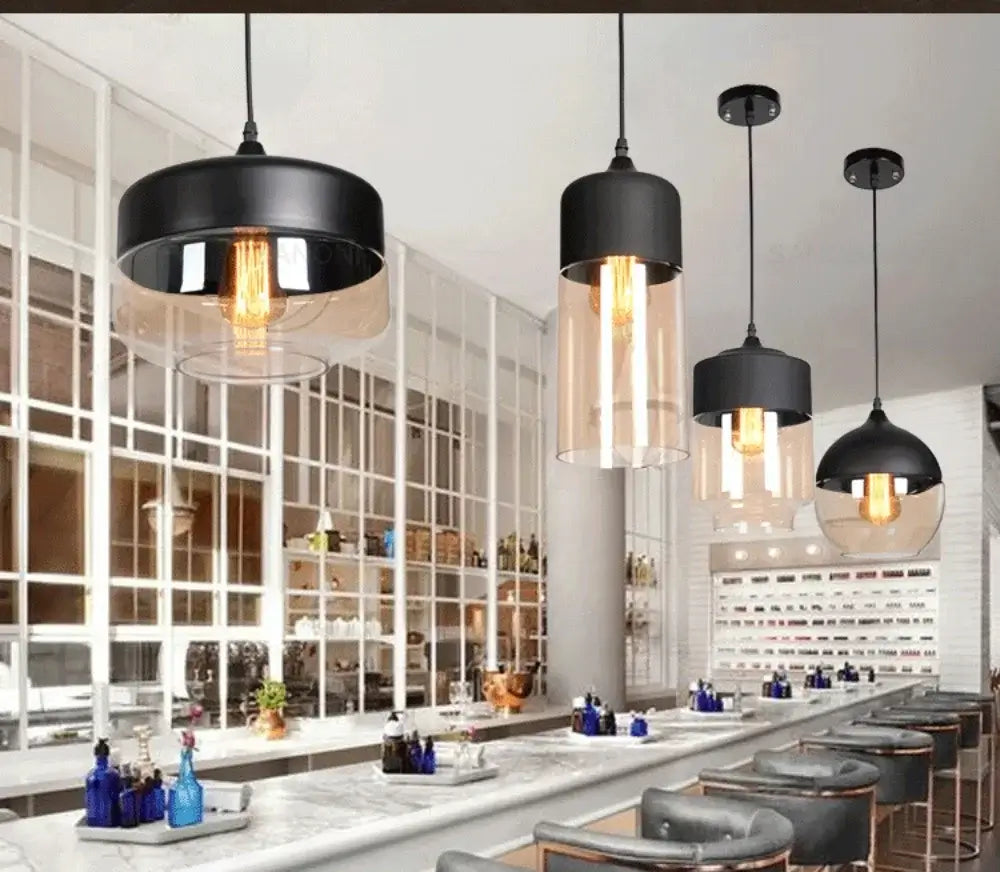 Modern pendant lights in a stylish bar setting, featuring black and glass designs illuminating the space.