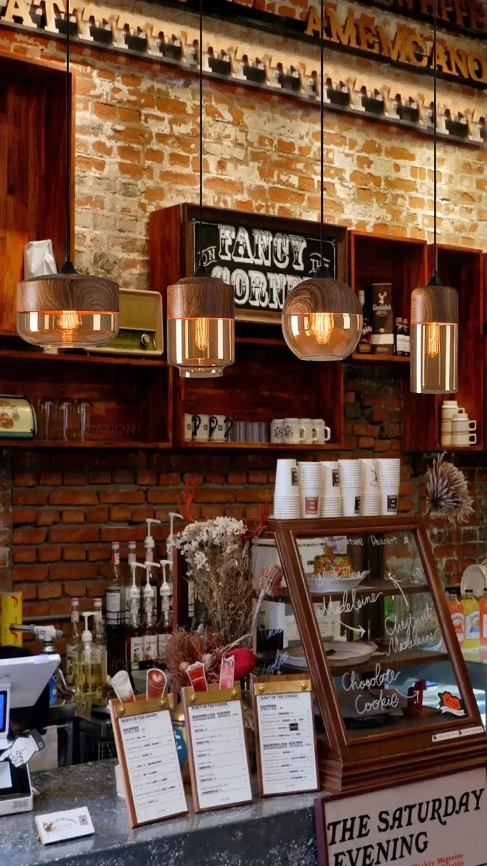 Modern Nordic pendant lights hanging above a cafe counter with a brick wall and menu display.