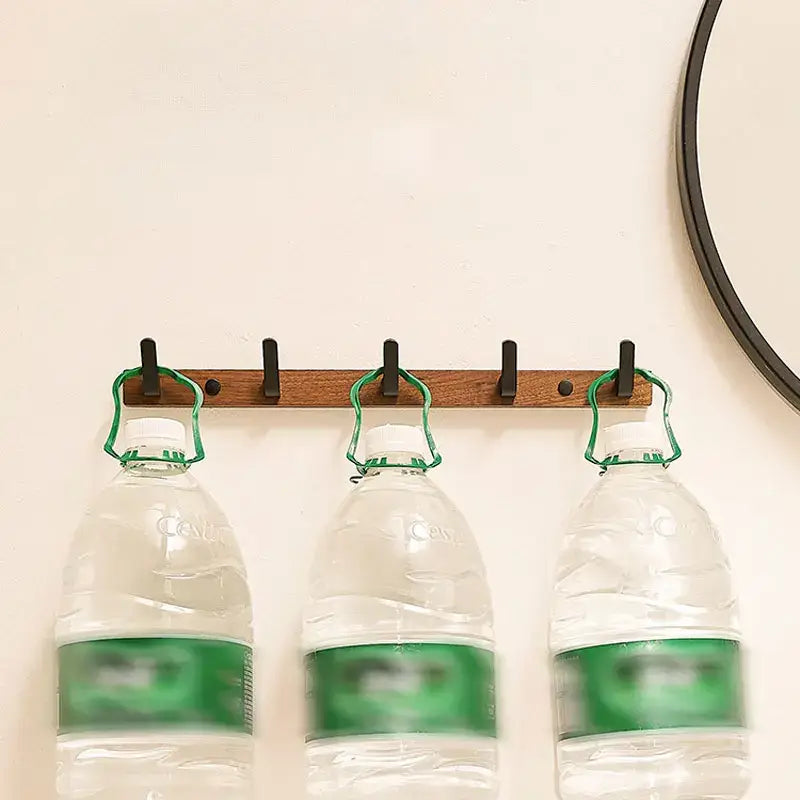 Wood black hook holding three water bottles, ideal for space-saving and organized home storage, by Housite.