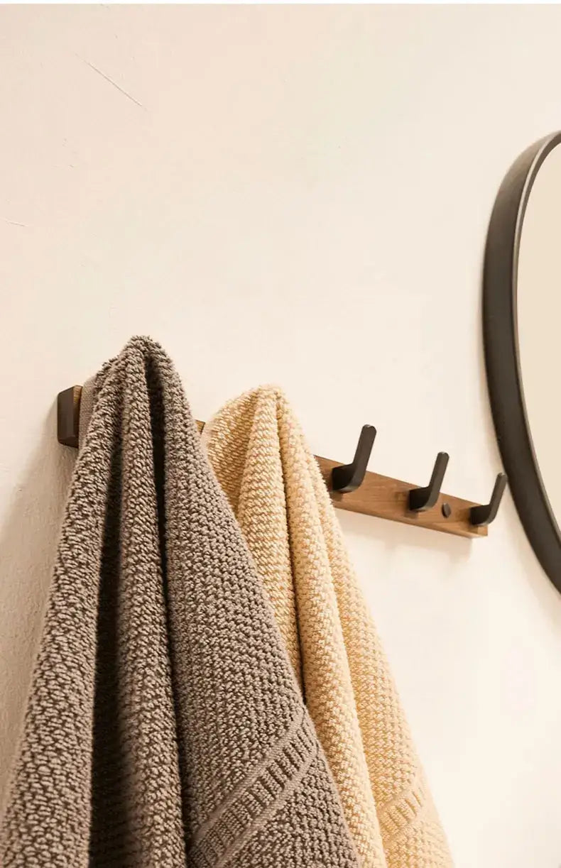 Wood black hook holding towels in a minimalist bathroom setting, ideal for space-saving organization by Housite.
