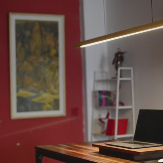 Wooden pendant light– Modern LED Hanging Lamp over a stylish workspace with red wall and plant.