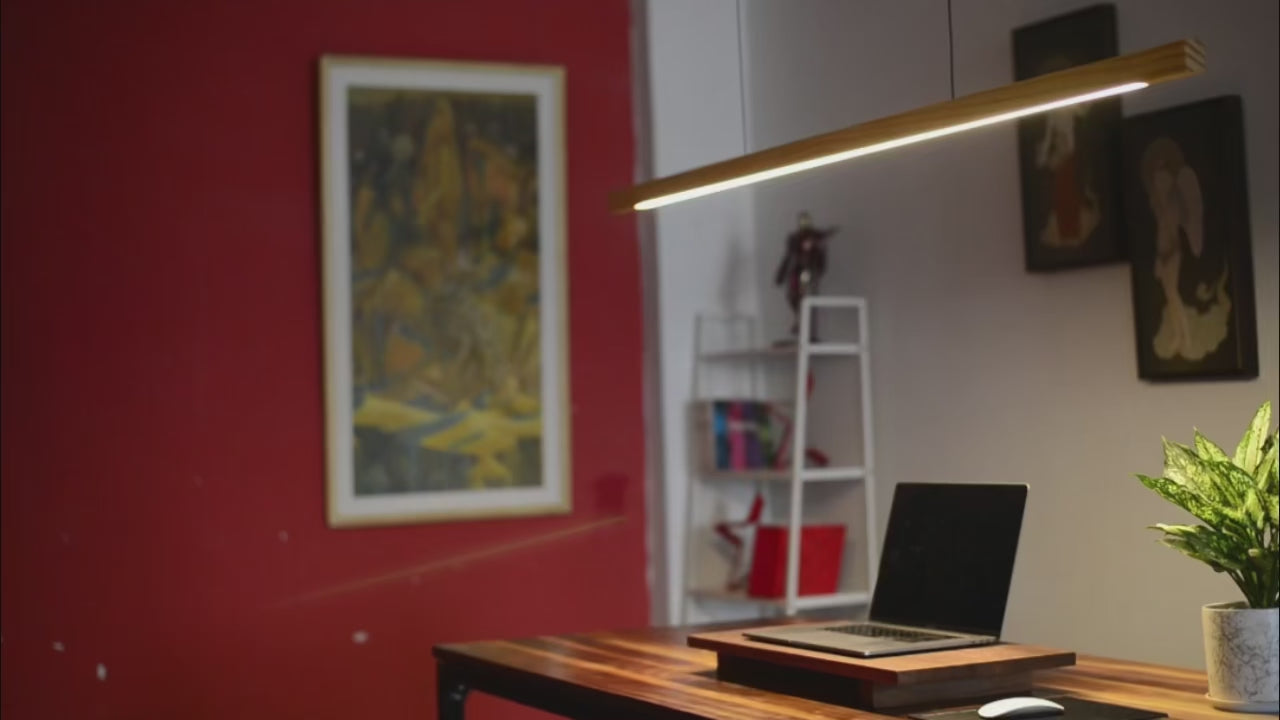 Wooden pendant light– Modern LED Hanging Lamp over a stylish workspace with red wall and plant.