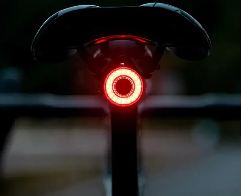 USB-C rechargeable bike tail light mounted on a bicycle saddle, glowing red for enhanced visibility and safety.