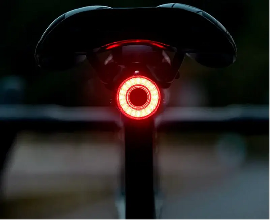 USB-C rechargeable bike tail light mounted on a bicycle saddle, glowing red for enhanced visibility and safety.