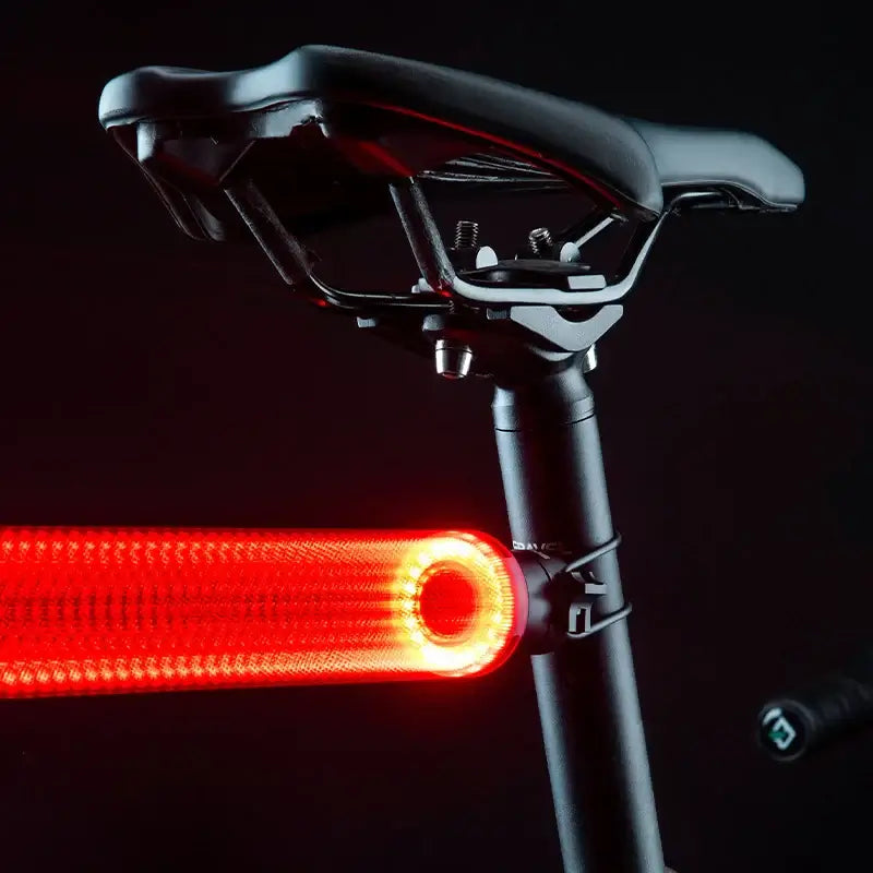 USB-C rechargeable bike tail light mounted on a bicycle saddle with a bright red glow for enhanced visibility.